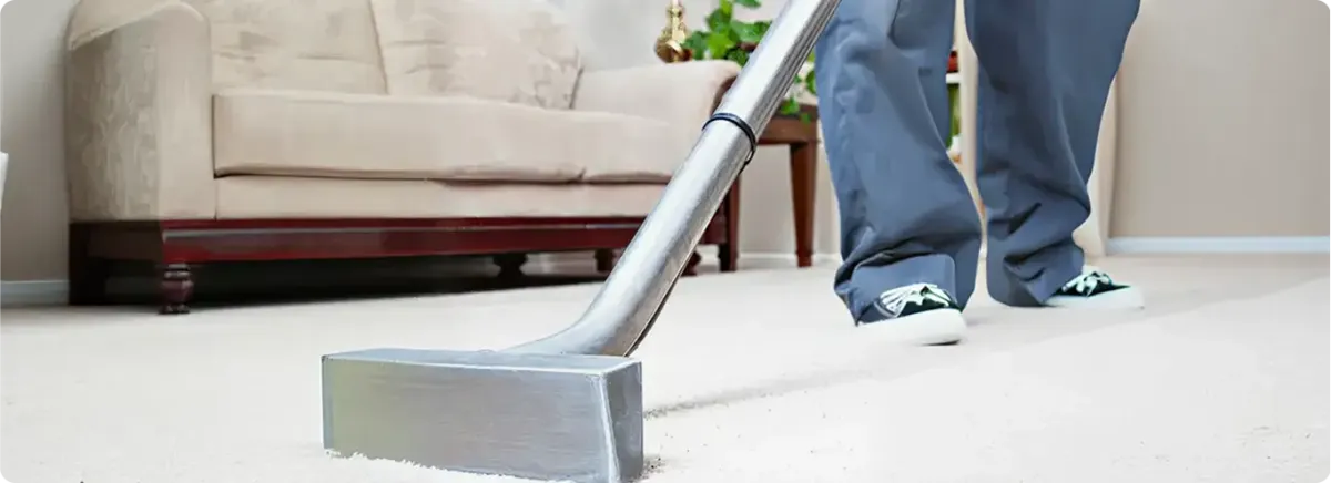 Carpet cleaning technician using a hot-water extraction wand on a light-colored carpet in a living room, Memphis, TN.