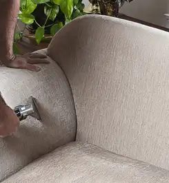 Professional upholstery cleaner deep-cleaning a fabric sofa with a handheld extraction tool and hose Memphis, TN.